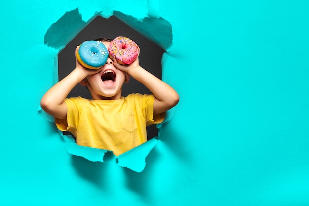 Happy cute boy is having fun played with donuts