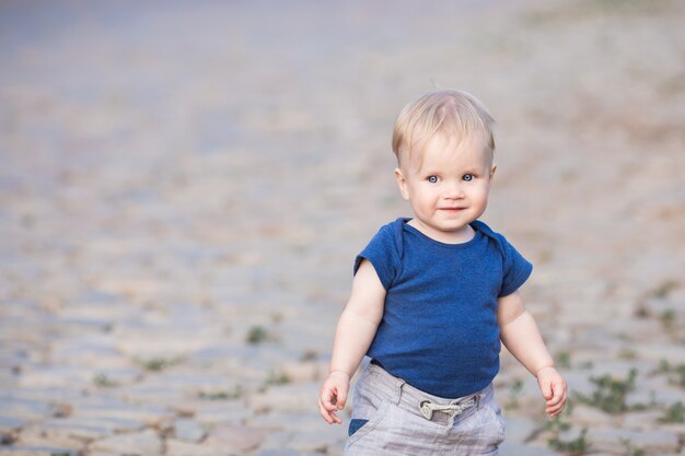 Happy cute boy on old roadway. Smiling one child outdoors on Road paved with stone on the sunset