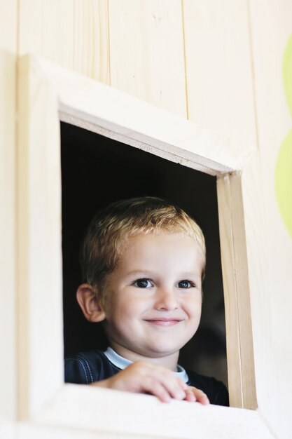 happy cute child in a wooden window at playground