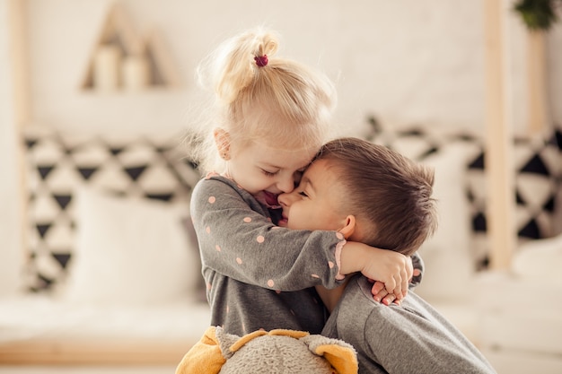 Happy cute children brother and sister in the nursery play and laugh, happy childhood