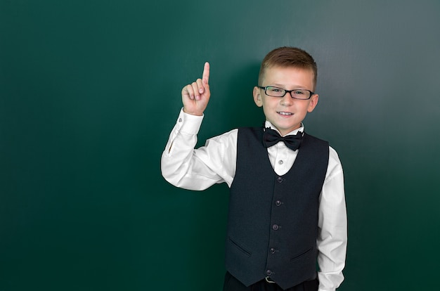 Happy cute clever boy with a bow tie and in glasses has an idea