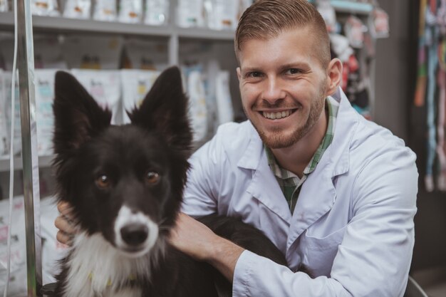 Cane sveglio felice che osserva alla macchina fotografica durante la visita medica all'ufficio del veterinario