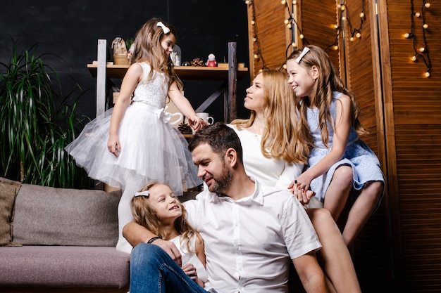 Happy cute family with three children exchanging gifts under the Christmas tree on the carpet.