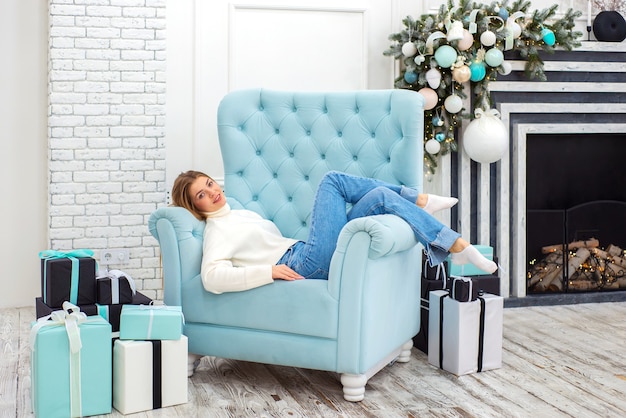 happy cute girl in christmas at home sitting in a chair near the christmas tree