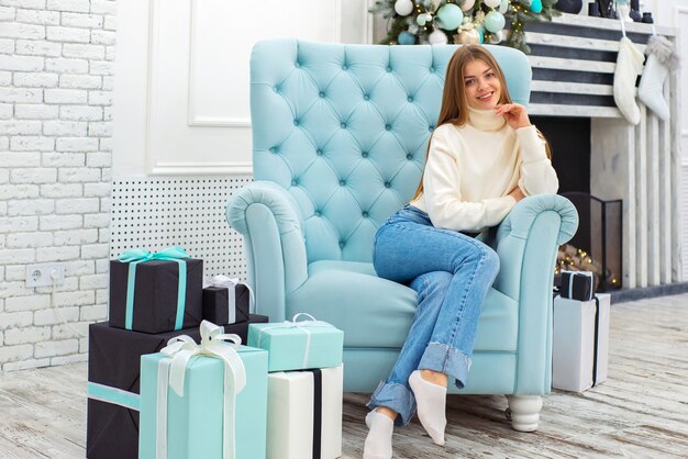 happy cute girl in christmas at home sitting in a chair near the christmas tree