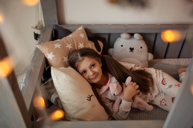 Счастливая милая девушка на кровати в пижаме на Рождество