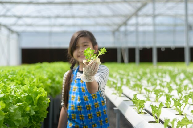 A happy cute girl learning and studying in hydroponic greenhouse farm, education and scientist concept