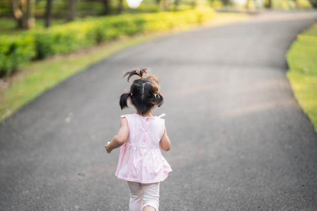 Ragazza carina felice che sorride e corre in giardino