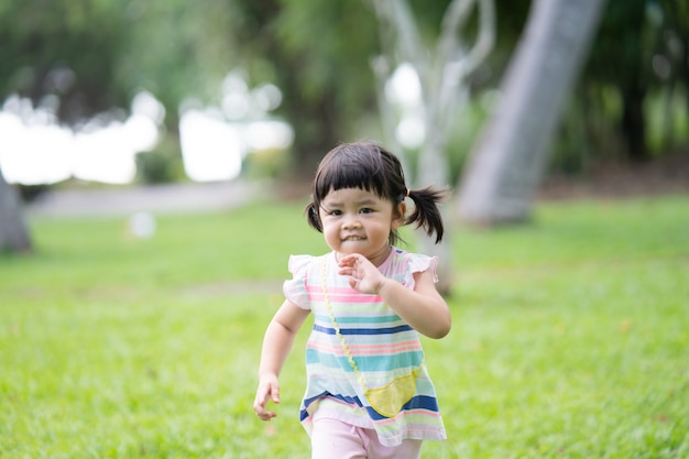 Happy cute girl smiling and running at the garden