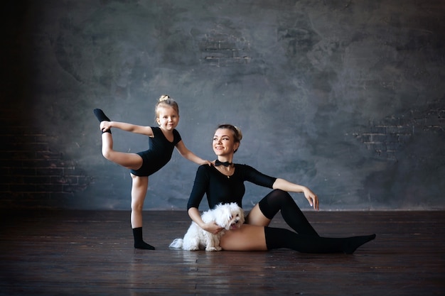 happy cute gymnasts mom and daughter with a white terrier dog