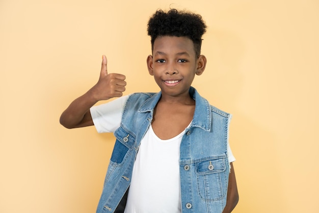 Happy cute kid boy with afro hair and jean shirt on yellow background