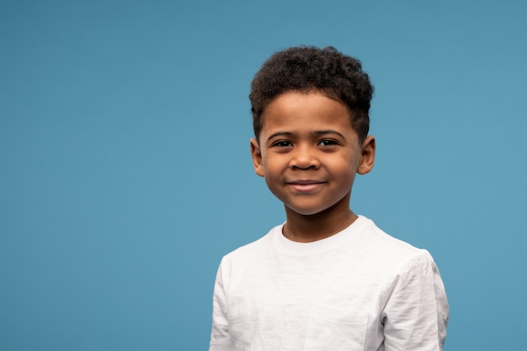Photo happy cute little boy of african ethnicity in white t-shirt on blue