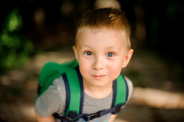 Photo happy cute little boy with a green backpack