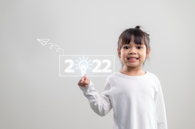 Счастливые милые маленькие дети улыбаются и трогают цифры 2022 года, выделенные на белом фоне для новогодних концепций