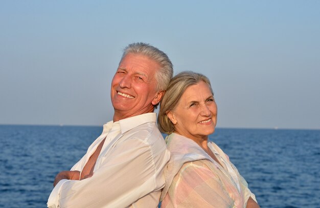 Happy cute senior couple at sea on sunset