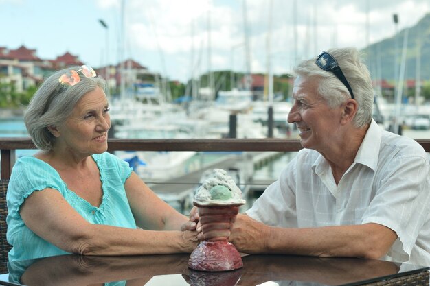 Photo happy cute senior couple sitting on the table on the pier