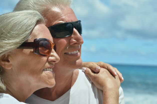 海でサングラスをかけた幸せなかわいい年配のカップル