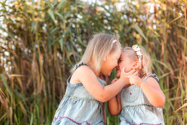 Happy cute smile adorable positive caucasian children having fun play outdoors hug together. Childhood, nature, vacation, kids lifestyle concept