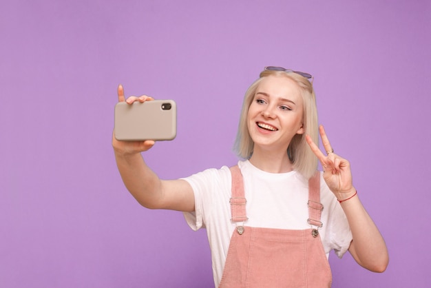 Happy cute woman in light casual clothing makes selfie