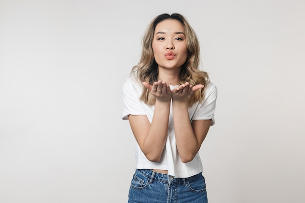 happy cute young woman posing isolated over white wall wall blowing kisses