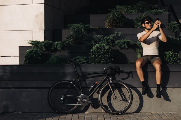 Happy cyclist using mobile after training outdoors