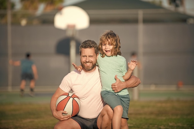 Happy dad and son playing basketball with ball outdoor family