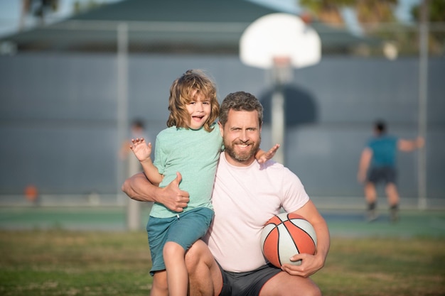 Happy dad and son playing basketball with ball outdoor family