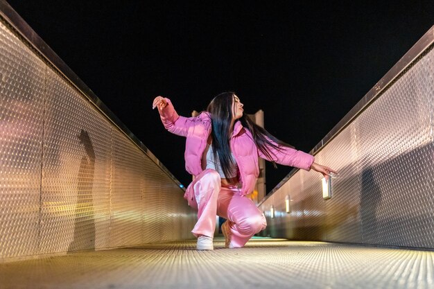 Happy dancer in squatting position on a bridge