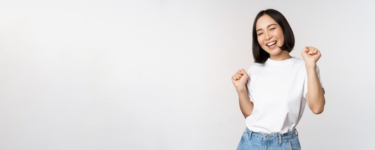 Photo tシャツを着て白い背景に対してポーズをとって幸せなダンス韓国の女の子