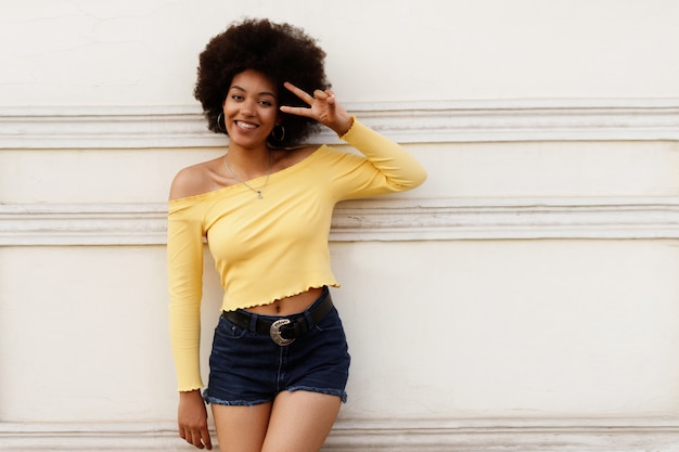 Happy dark-skinned girl against the wall.