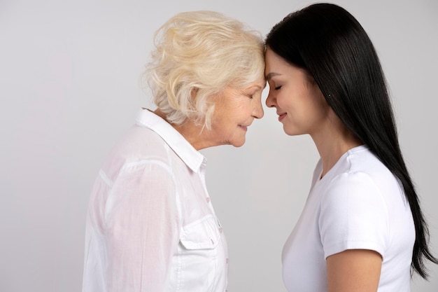 Happy daughter standing forehead to forehead with her mature mother isolated Smiling adult woman posing with senior mother feel thankful grateful Motherhood family unity concept