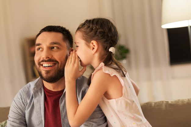 happy daughter whispering secret to father at home