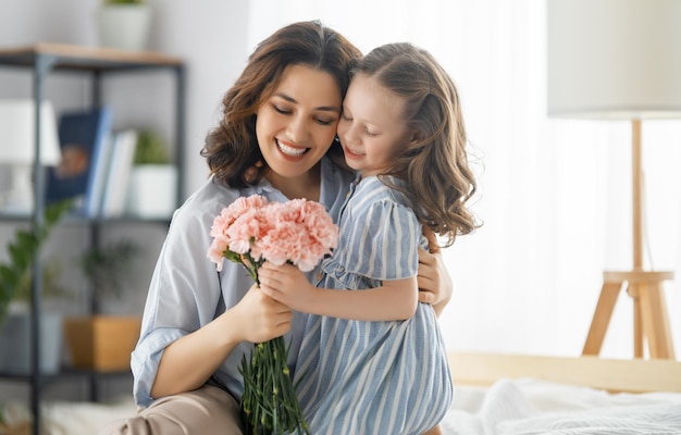 Happy day Child daughter is congratulating mother and giving her flowers Mum and girl smiling