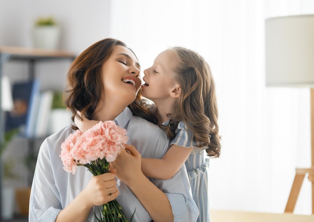 Happy day Child daughter is congratulating mother and giving her flowers