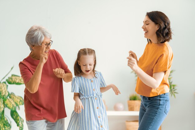 幸せな日おばあちゃんの母と娘の子の女の子が笑顔で踊って遊んでいます