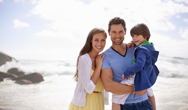 Happy days filled with sunshine Portrait of a happy family standing together on the beach