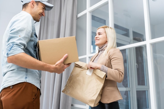 Happy deliverer carrying packages while making home delivery to his customer.