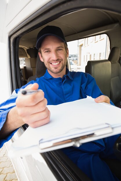 Happy delivery man showing clipboard to sign to customer