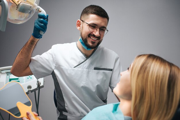 Photo happy dentist sitting beside client and looking at her