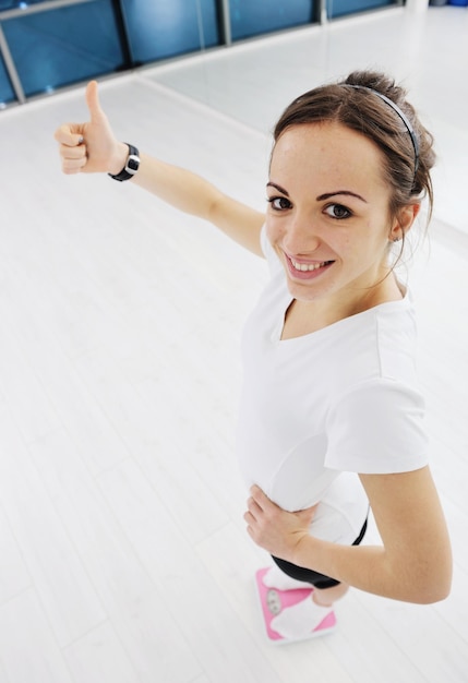 happy diet concept with young woman on pink scale at sport fitnes gym club