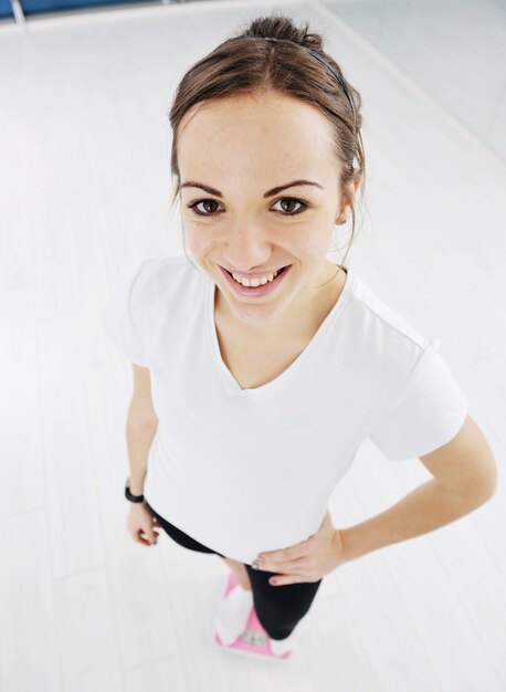 Photo happy diet concept with young woman on pink scale at sport fitnes gym club