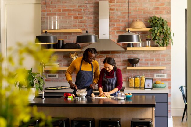 Happy diverse couple baking christmas cookies making dough in kitchen copy space