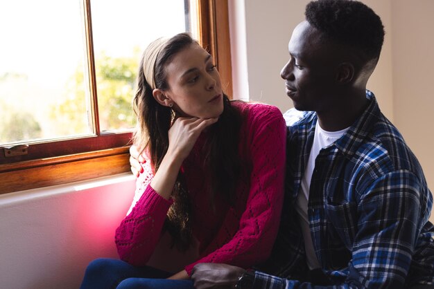 Photo happy diverse couple embracing next to window at home