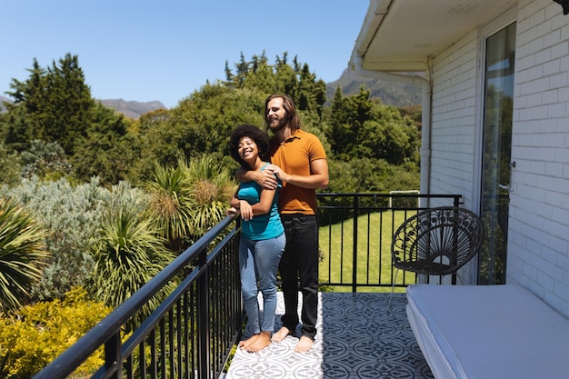 Photo happy diverse couple standing on balcony embracing and smiling