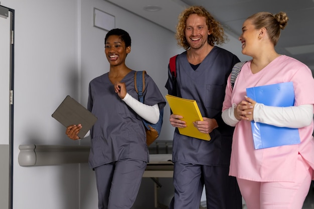 Happy diverse doctors wearing scrubs walking through corridor at hospital