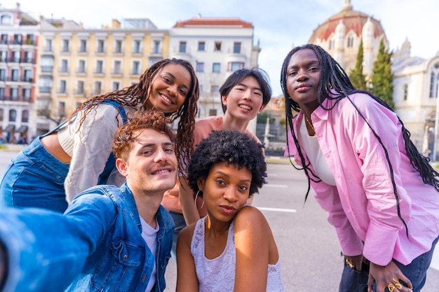 Happy diverse friends taking a selfie in the city