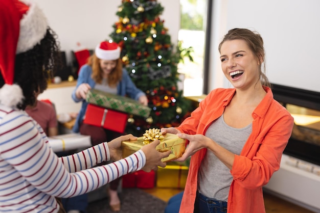 Happy diverse friends with santa hats and gifts at christmas
