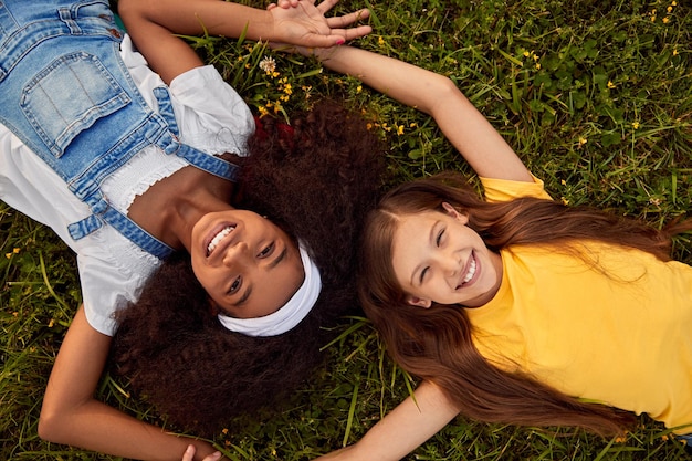 Happy diverse girlfriends lying on grass