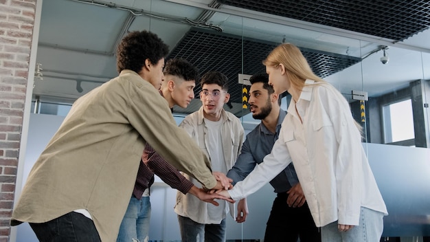 Foto gli studenti di uomini d'affari di gruppo eterogeneo felice impilano le mani insieme motivano per il successo partecipare