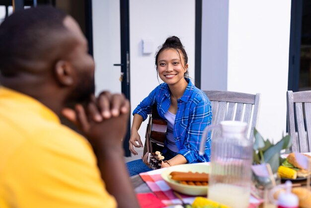 Photo happy diverse group of friends playing guitar and having dinner